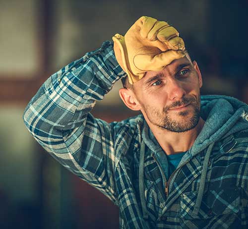 Man in work clothes wiping sweat from his brow