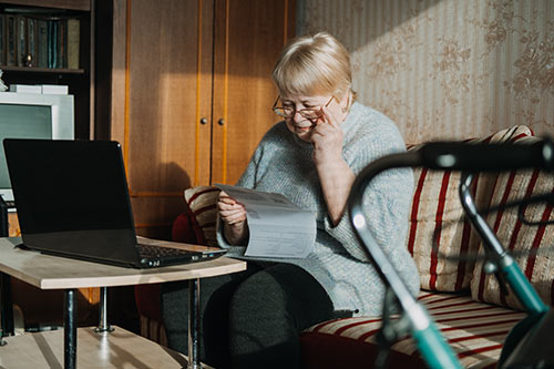 Disabled woman with a walker looking in dismay at her disability claim paperwork