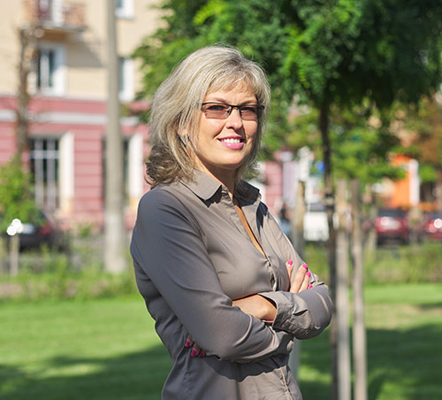 Woman in her 40s standing outside an office building, smiling before she goes in to work