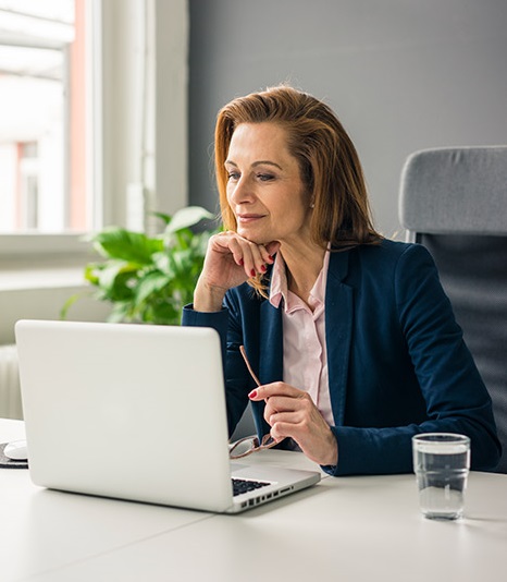 Client Jessica, a 42-year-old woman with long reddish blonde hair, sitting at the computer in her home office