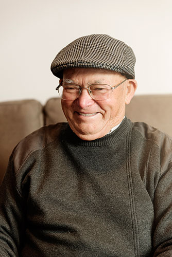 Our senior client Martin wearing a dapper cap and green sweater