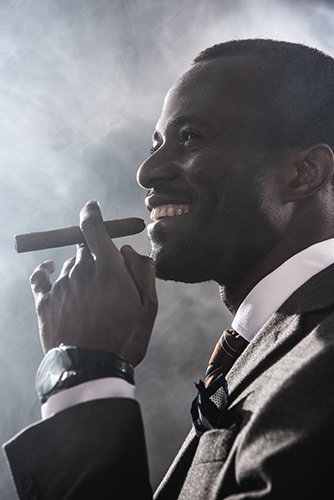 Man in a suit smoking a cigar, smiling