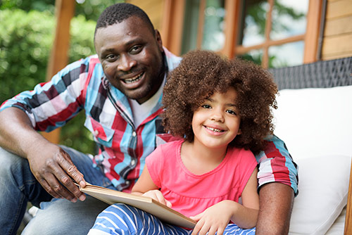 Dad and daughter sitting outside reading together