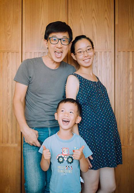 Portrait of a family of three - Dad is making a funny face, while Mom and their son smile for the camera