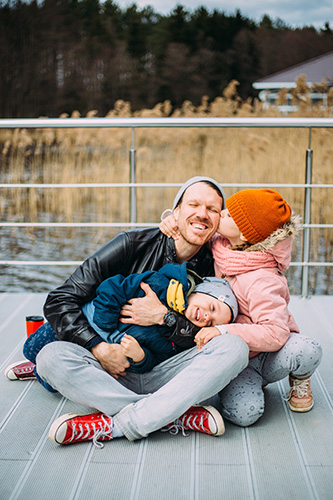 Man sitting with his two small daughters on the deck of his home