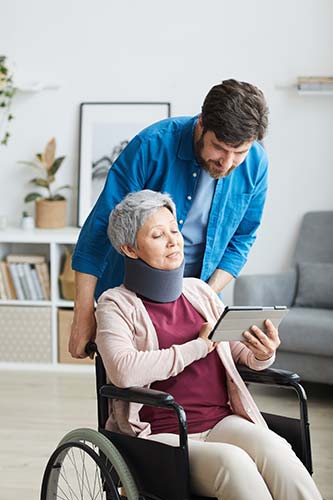 Senior woman wearing a neck brace using a tablet to look up ‘Does Medicare cover disability insurance?’