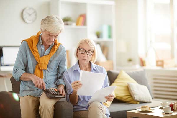 Senior couple at home, looking through their SSDI statements as they do their taxes
