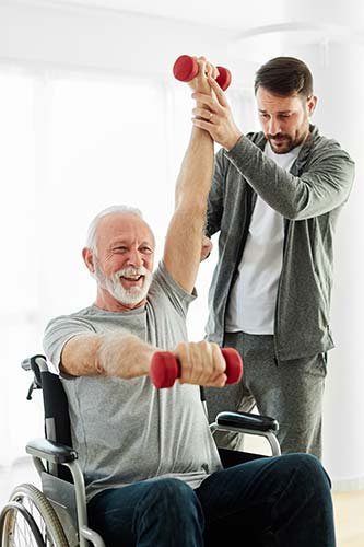 Disabled senior man in a wheelchair doing physical therapy with dumbbells