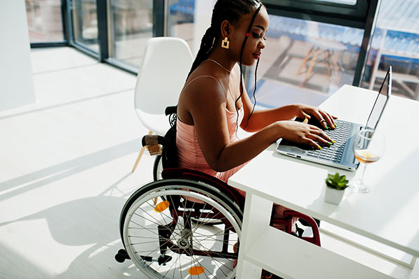 Young woman in a wheelchair using her laptop to look up social security disability insurance