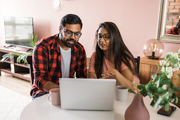 Young couple looking up ‘How does whole life insurance work’ on their laptop