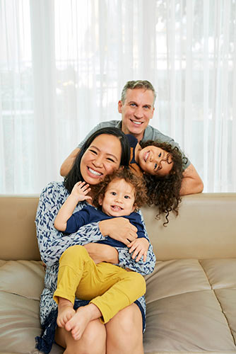 Young parents playing with their two kids on the couch