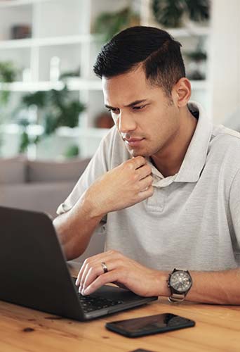 Young man looking up reasons to buy whole life insurance on his laptop