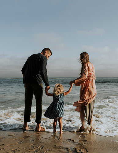 Happy couple with their young daughter walking on the beach
