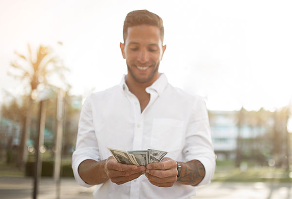 Man holding a handful of cash, representing the cash value component of whole life insurance