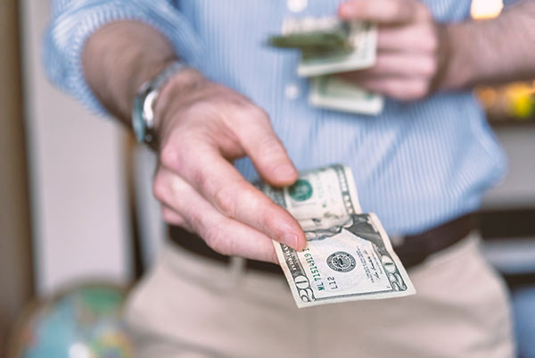 Close-up of a man’s hand holding out cash