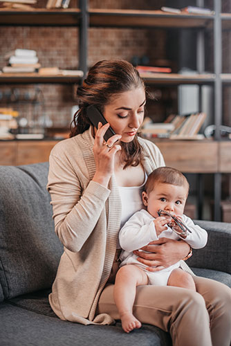 Mom holding her young son while she calls a life insurance agent to get help choosing between term and permanent life insurance