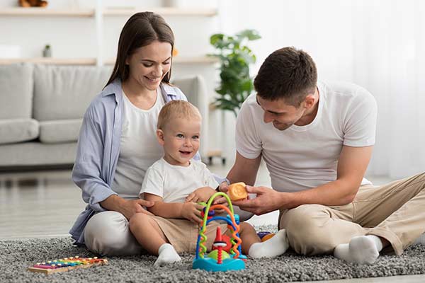 Happy couple playing on the floor with their toddler