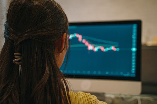 Woman looking at a screen showing a stock market chart