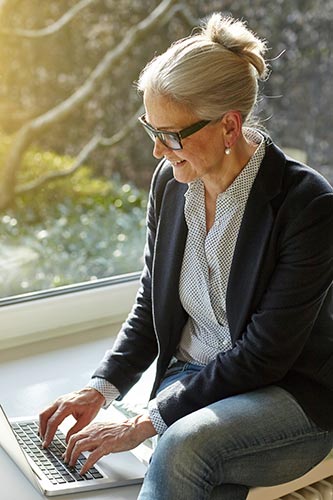 Senior woman looking up her retirement account details on a laptop