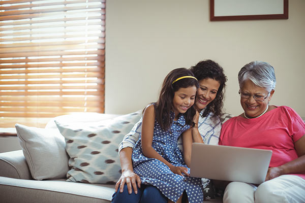 Multi-generational family with grandma, mom, and daughter using a laptop to get a quote for whole life insurance and term life insurance to compare costs