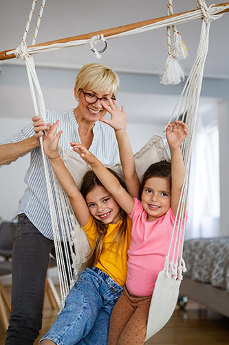 Grandma playing with her two granddaughters using an indoor swing
