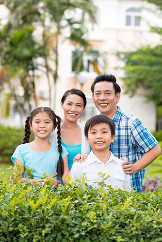 Happy Asian family of four standing outside in their yard