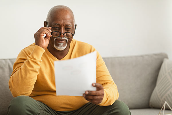Senior man reading his term life insurance policy documents to find out if he has a provision to convert to a permanent policy