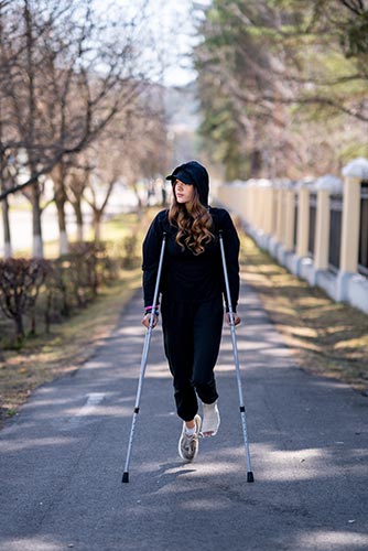 Woman with a broken ankle walking with crutches