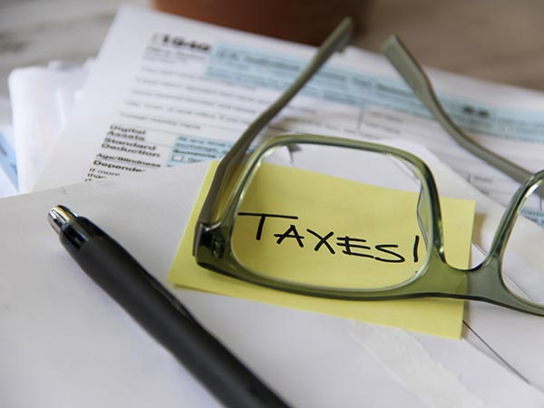 IRS tax form 1040 lying on a table with a sticky note that says ‘taxes’