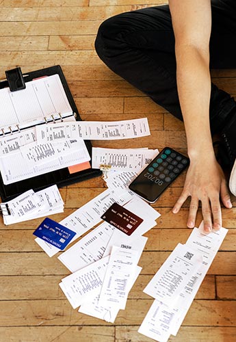 Man paying bills with receipts and credit cards spread out on the floor around him