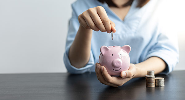 Woman putting a coin in a piggy bank, symbolizing term life as the cheapest type of life insurance