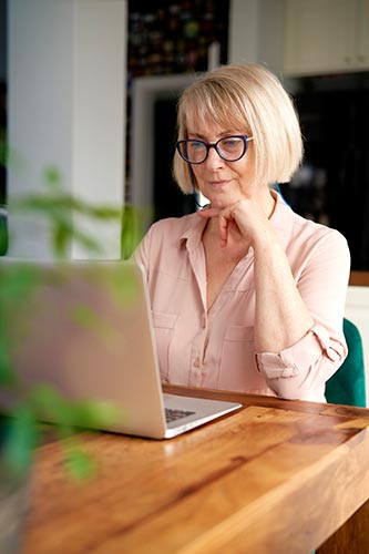 Senior woman researching single premium life insurance on her laptop