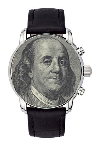 Close-up of a watch with its face covered by Benjamin Franklin’s face on the $100 bill