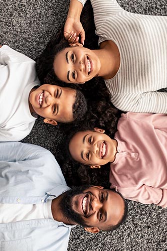 Family of four laying on the carpet smiling