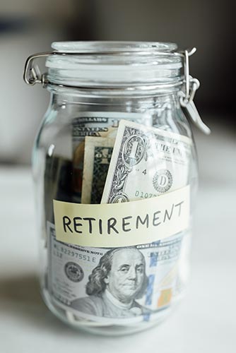 Glass jar stuffed with money and labeled ‘retirement’
