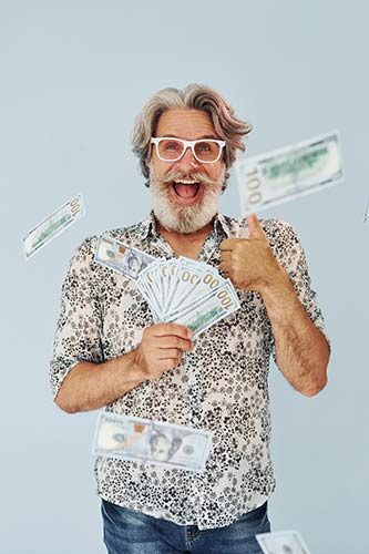 Senior man holding a fan of $100 bills and smiling at the camera